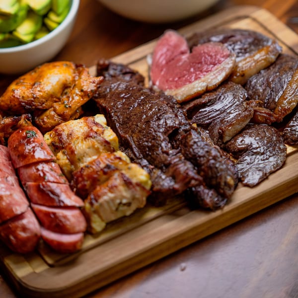 A wooden board filled with various grilled Brazilian meats, including steak, chicken, and sausage.